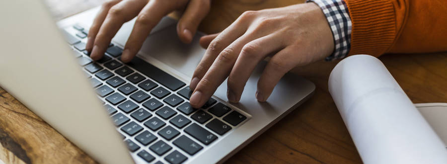 Man In Orange Sweater Typing On Computer Thumbnail